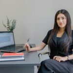Woman professional reviewing business documents and a laptop at her desk